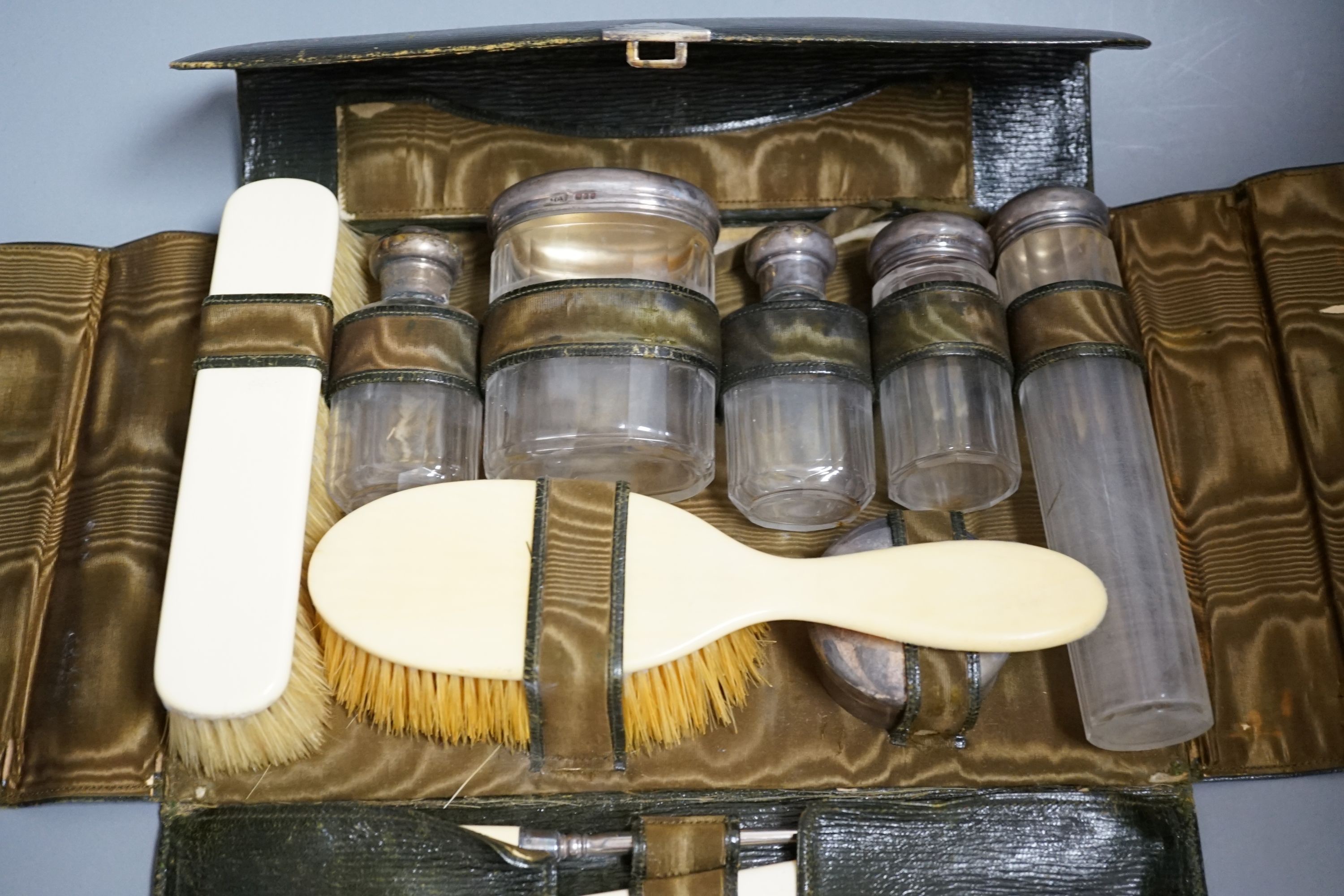 A George V J.C. Vickery leather travelling vanity case, containing five silver mounted toilet jars, silver box and twelve other accoutrements, London, 1910, case 29cm.